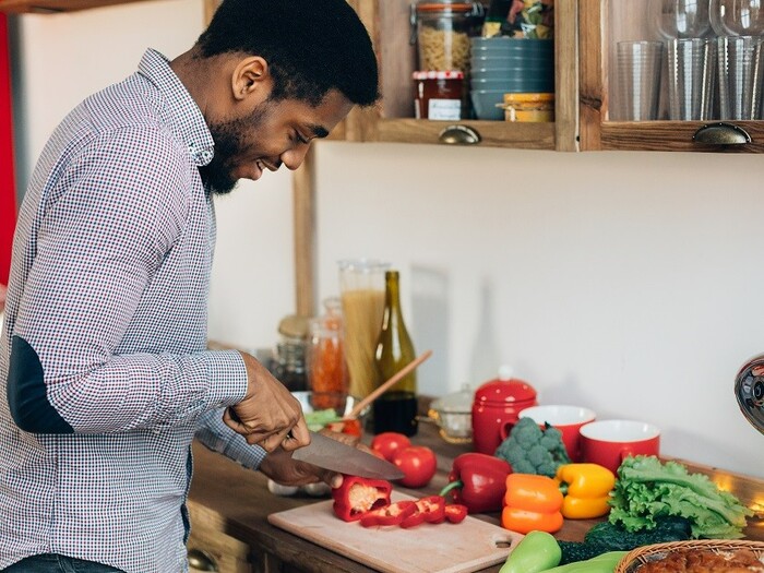 Cook a Meal : African-american man preparing delicious and healthy food in kitchen, cutting fresh vegetables, copy space