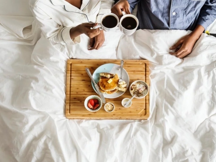 Breakfast in Bed: Bright color breakfast in bed. Toast with strawberry, blueberry, black raspberry and a cup of tea in clear glass cup on a wooden tray