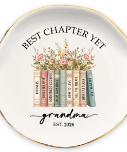 Personalized grandma jewelry dish with gold trim, floral watercolor design and a row of storybook-style books reading "Kindness," "How To Love," and "Full Hearted," personalized with "grandma Est. 2026" and the phrase "Best Chapter Yet"